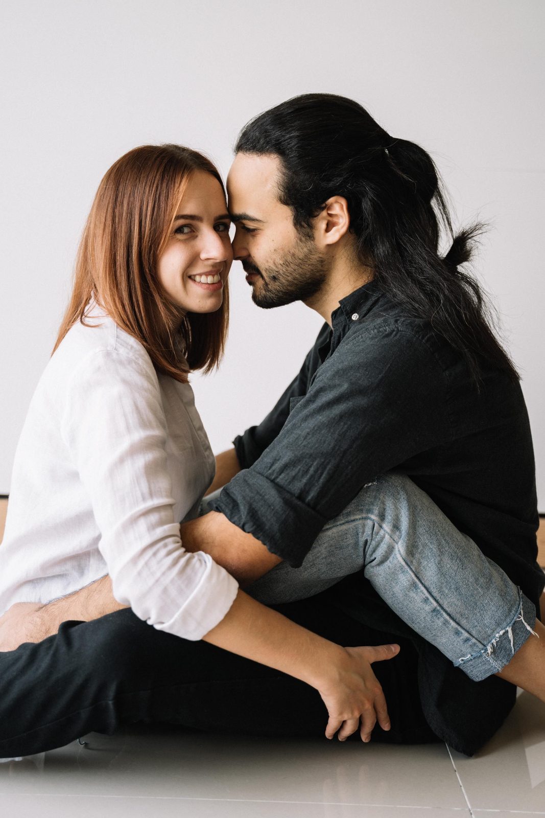 A couple sitting close together, foreheads nearly touching